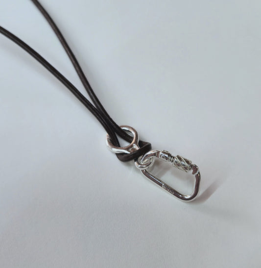 Close-up of a silver figure 8 descender and functional carabiner on a brown cord against a light gray background
